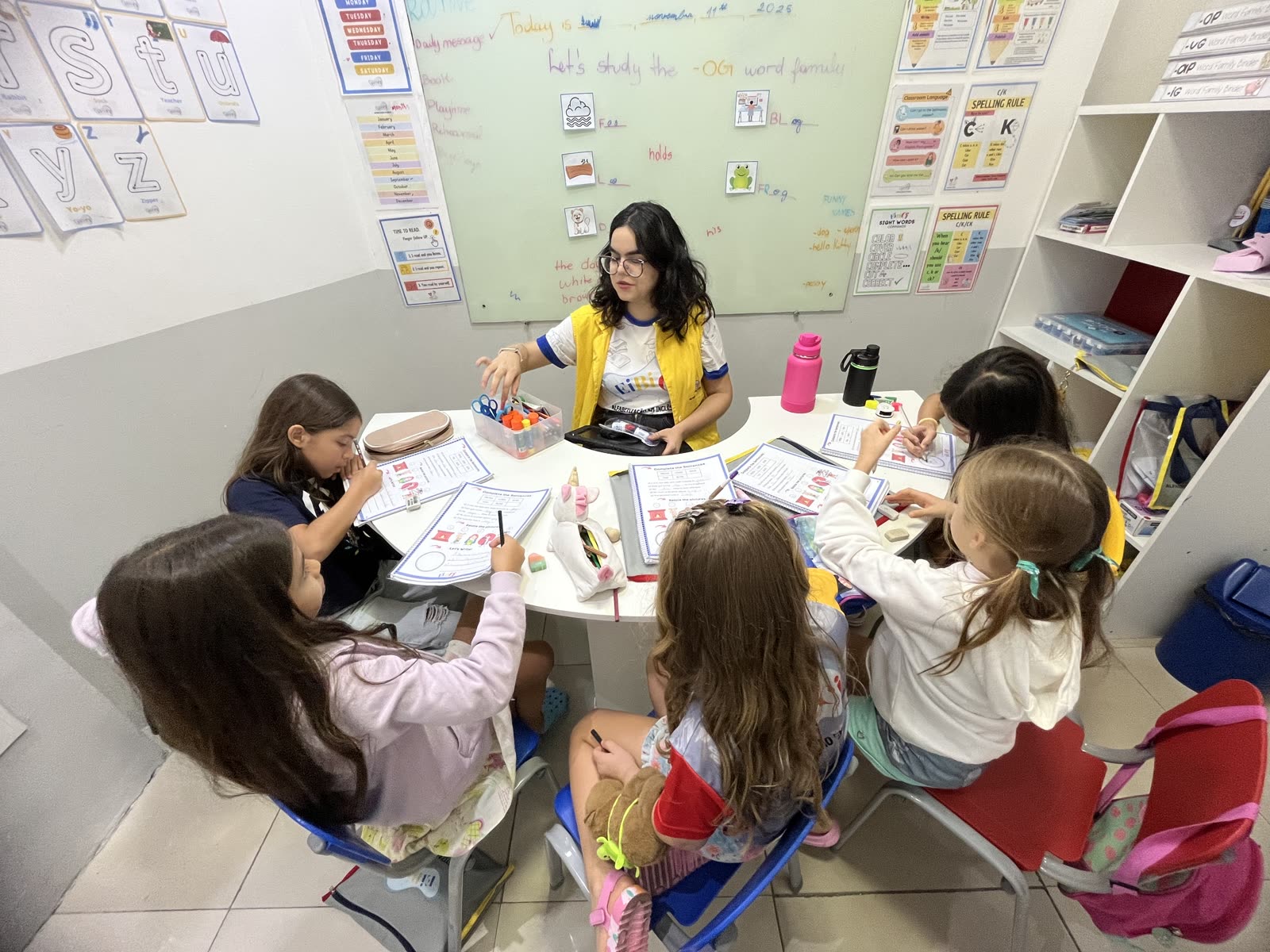Crianças em atividade de inglês com material colorido na mesa
